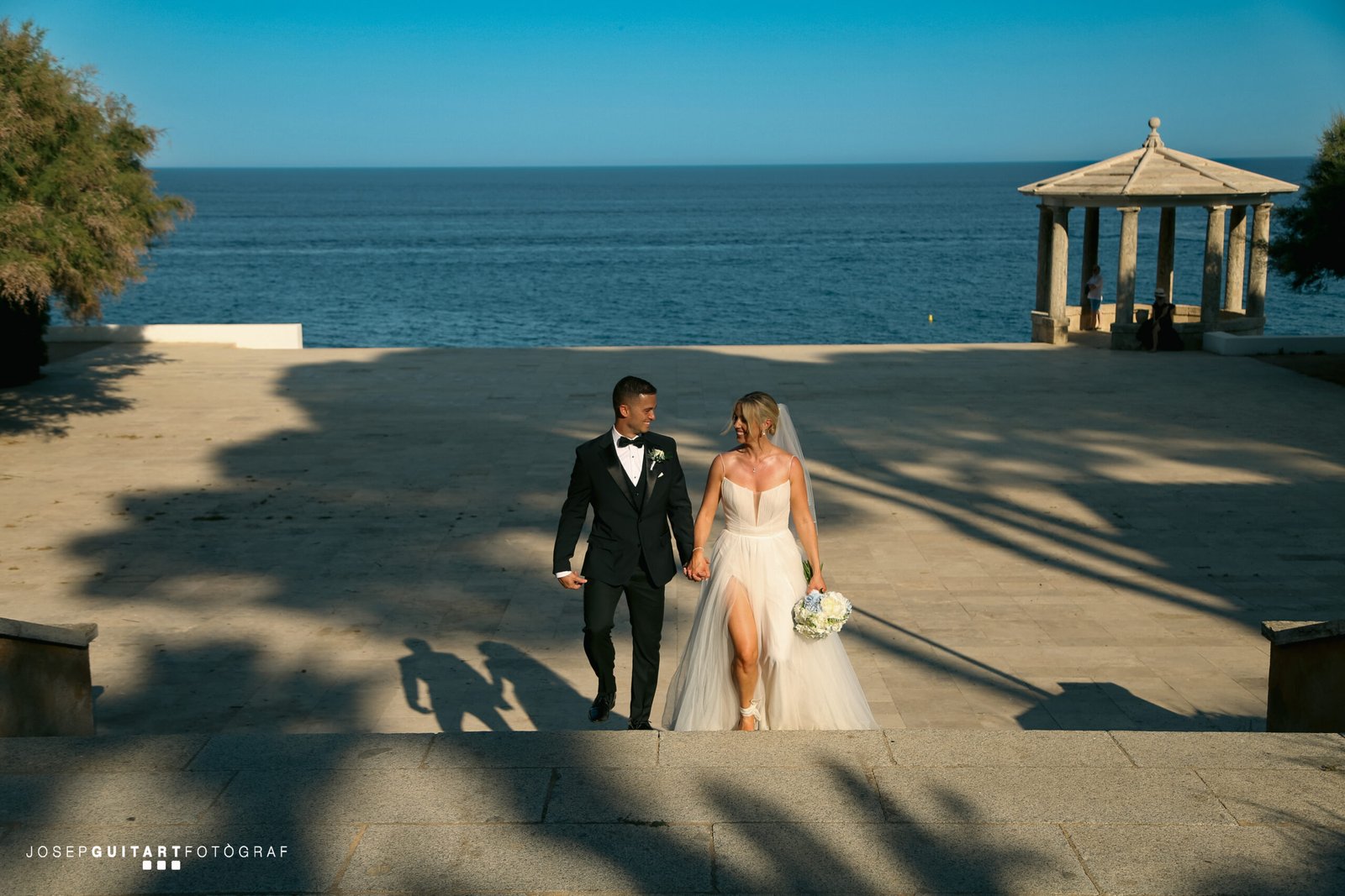 Elegant and romantic bride and groom couple with the blue Mediterranean Sea in the background at a destination wedding in Barcelona